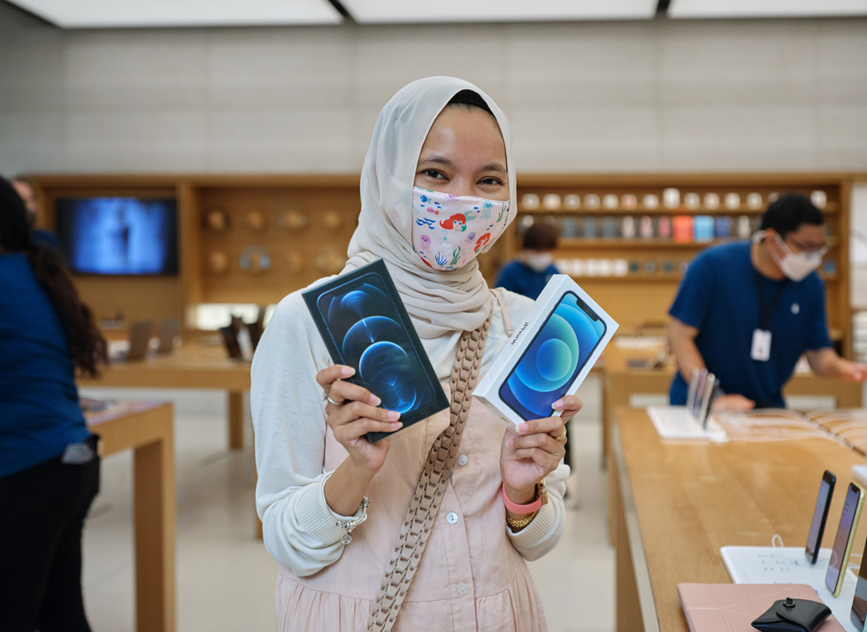 Молодой покупатель на Apple Orchard Road с новым iPhone 12 и iPhone 12 Pro.
