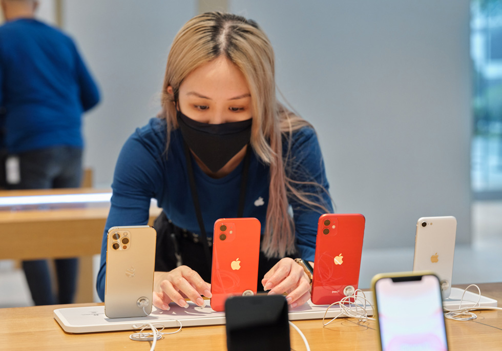 Член команды Apple Orchard Road настраивает дисплей iPhone SE, iPhone 11, iPhone 12 и iPhone 12 Pro.