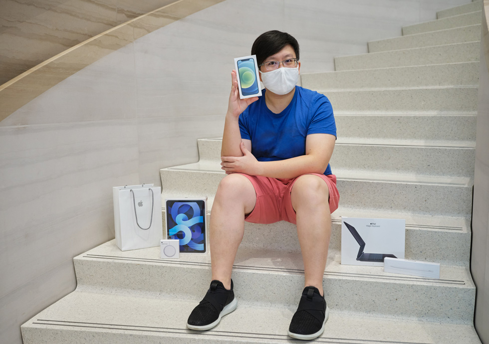 Покупатель в Apple Orchard Road демонстрирует свой новый iPhone 12, iPad Air и зарядное устройство MagSafe
