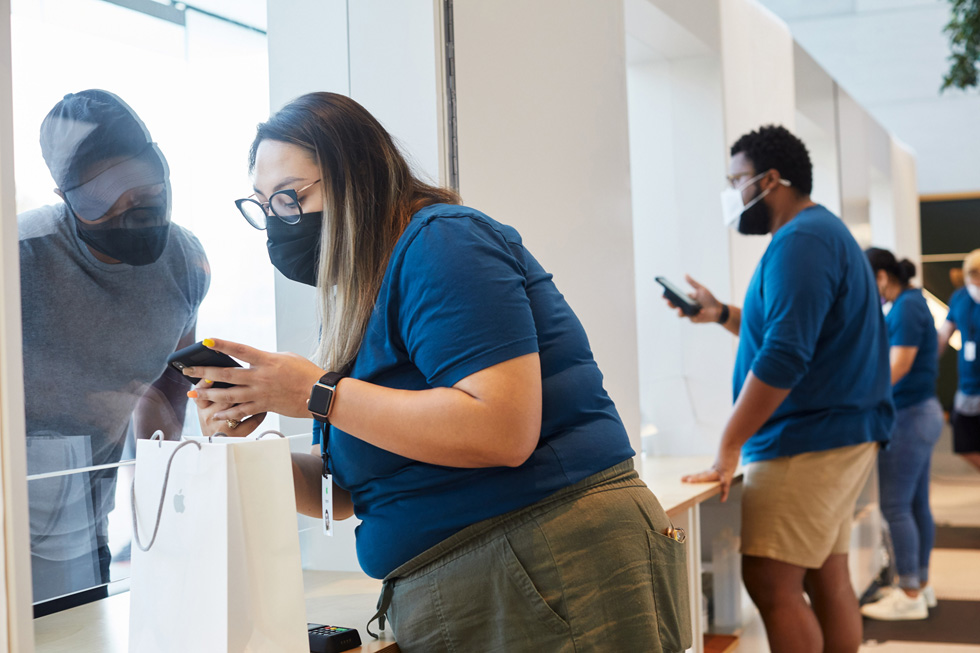 Сотрудник Apple помогает покупателю с покупкой Apple в Apple Highland Village.